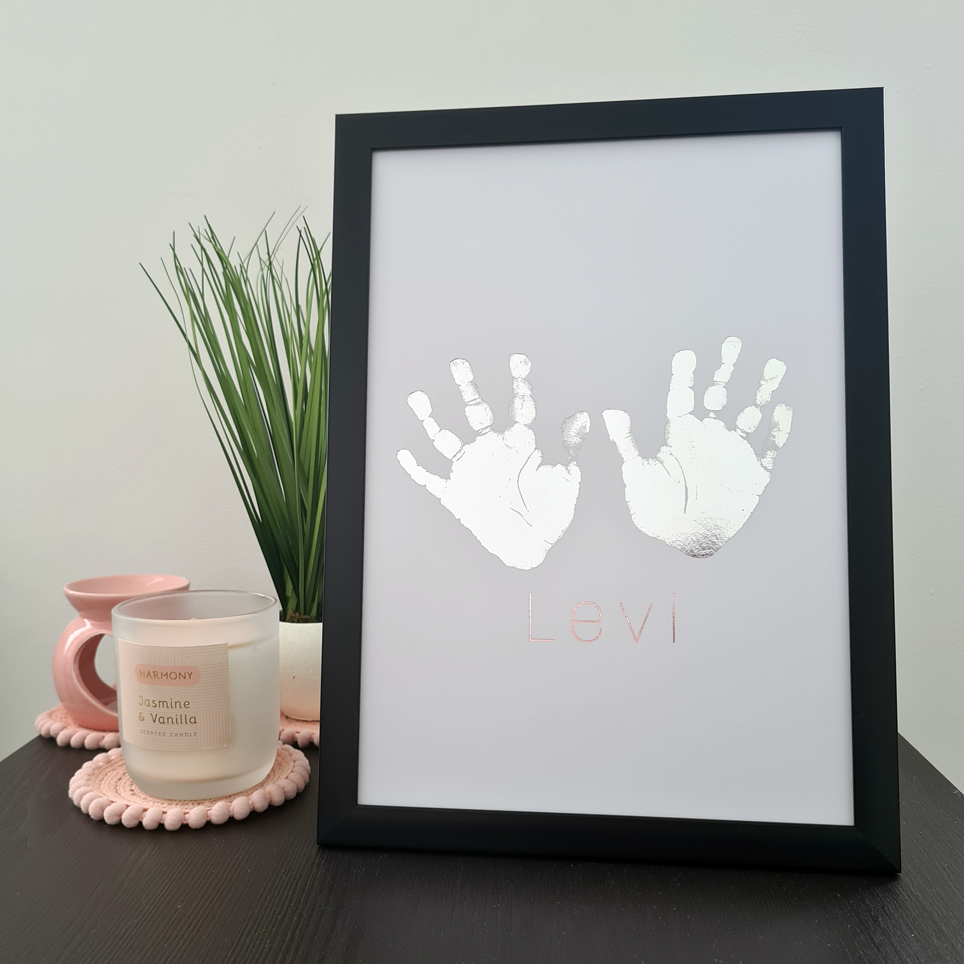 Black framed personalised handprints in silver foil on a table