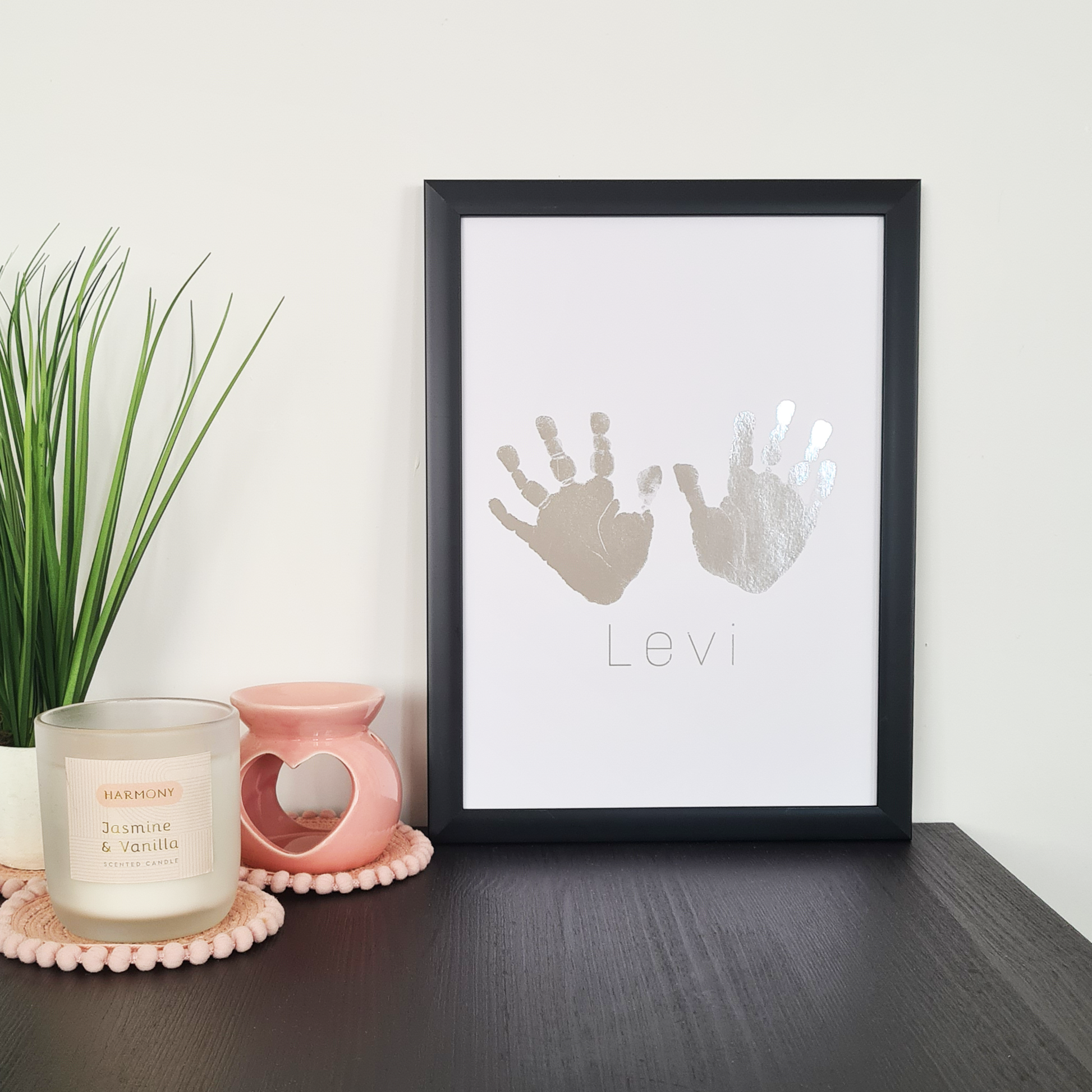 Black framed personalised handprints in silver foil on a table