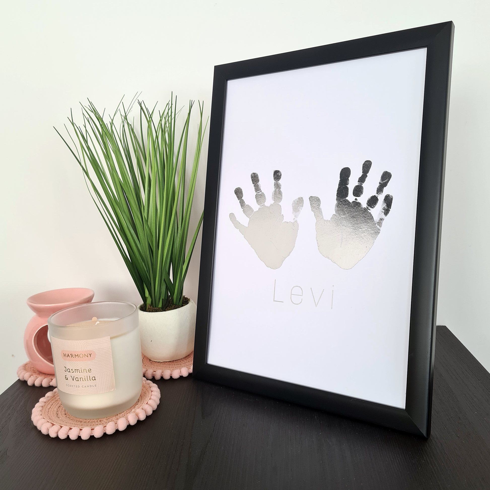 Black framed personalised handprints in silver foil on a table