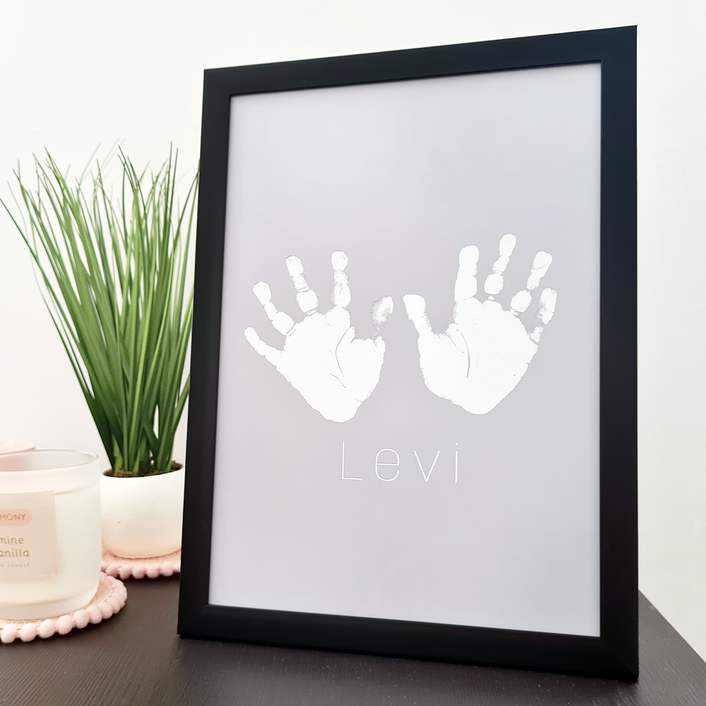 Black framed personalised handprints in silver foil on a table