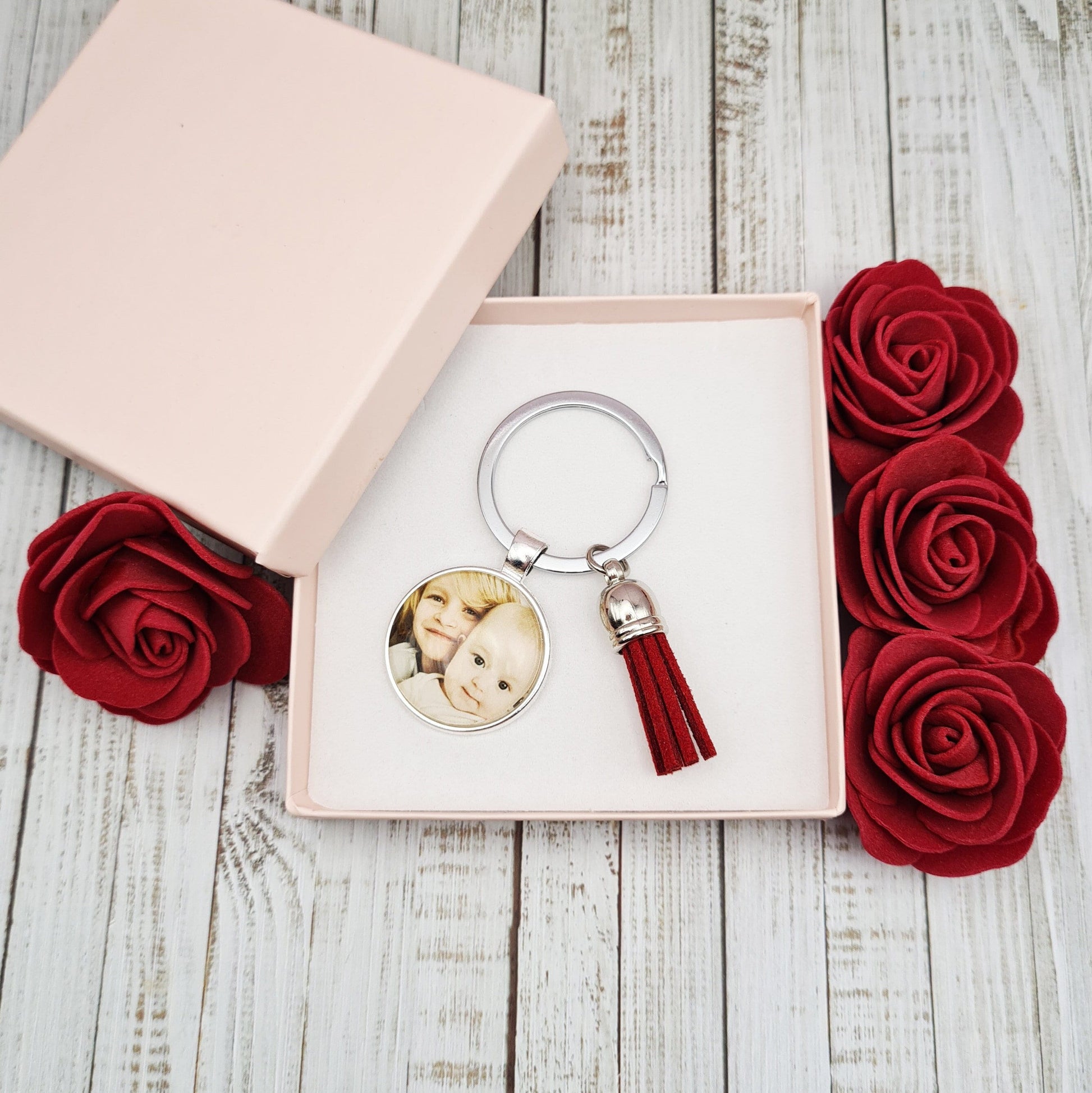 Silver key ring with pendant personalised with a photo and a tassel inside a pink gift box