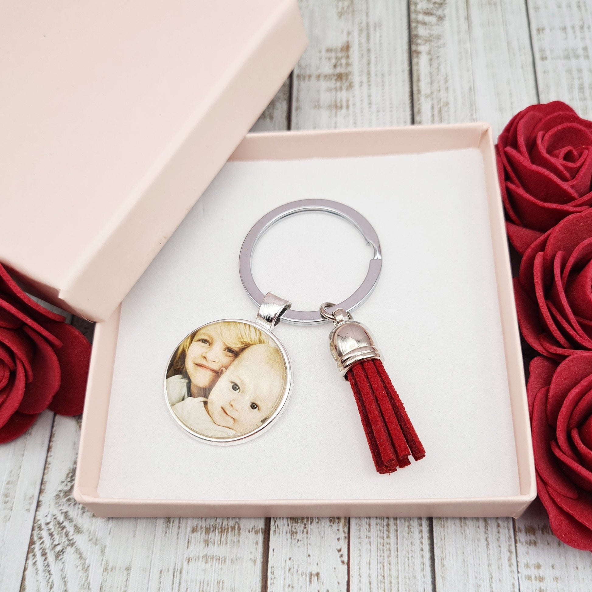 Silver key ring with pendant personalised with a photo and a tassel inside a pink gift box